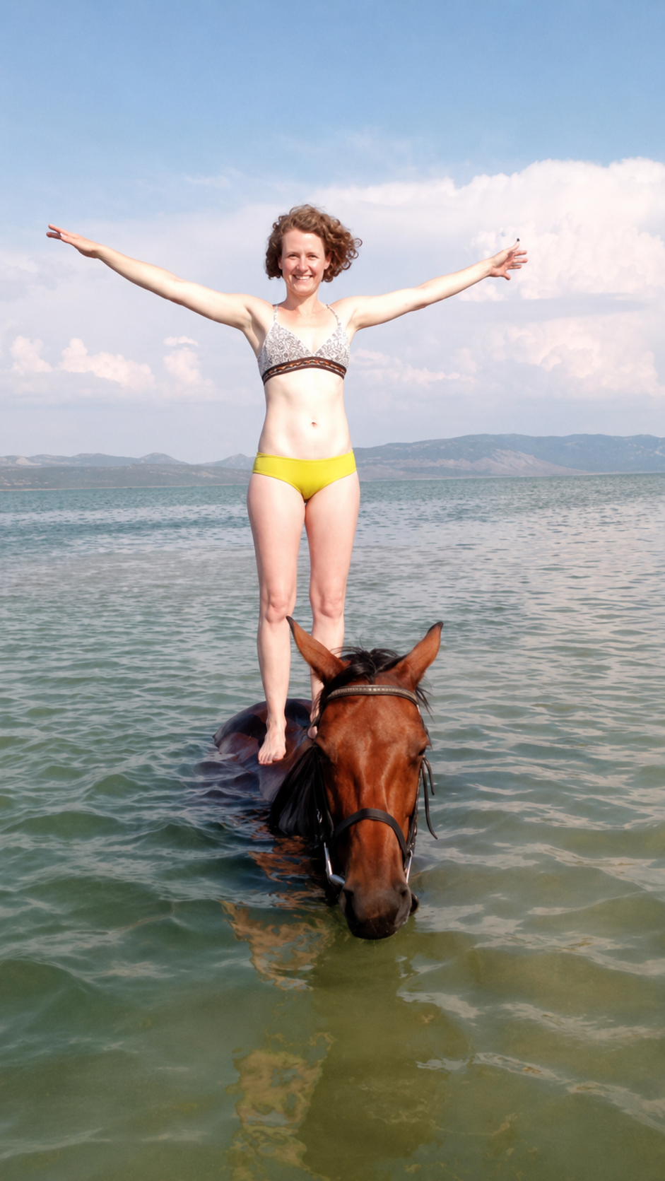 Greta Marie steht mit ausgebreiteten Armen auf ihrem Pferd Tolkien im Wasser